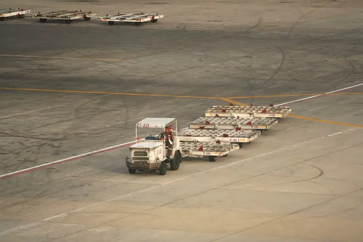 Personal de asistencia en tierra manejando equipaje en terminal de aeropuerto.
