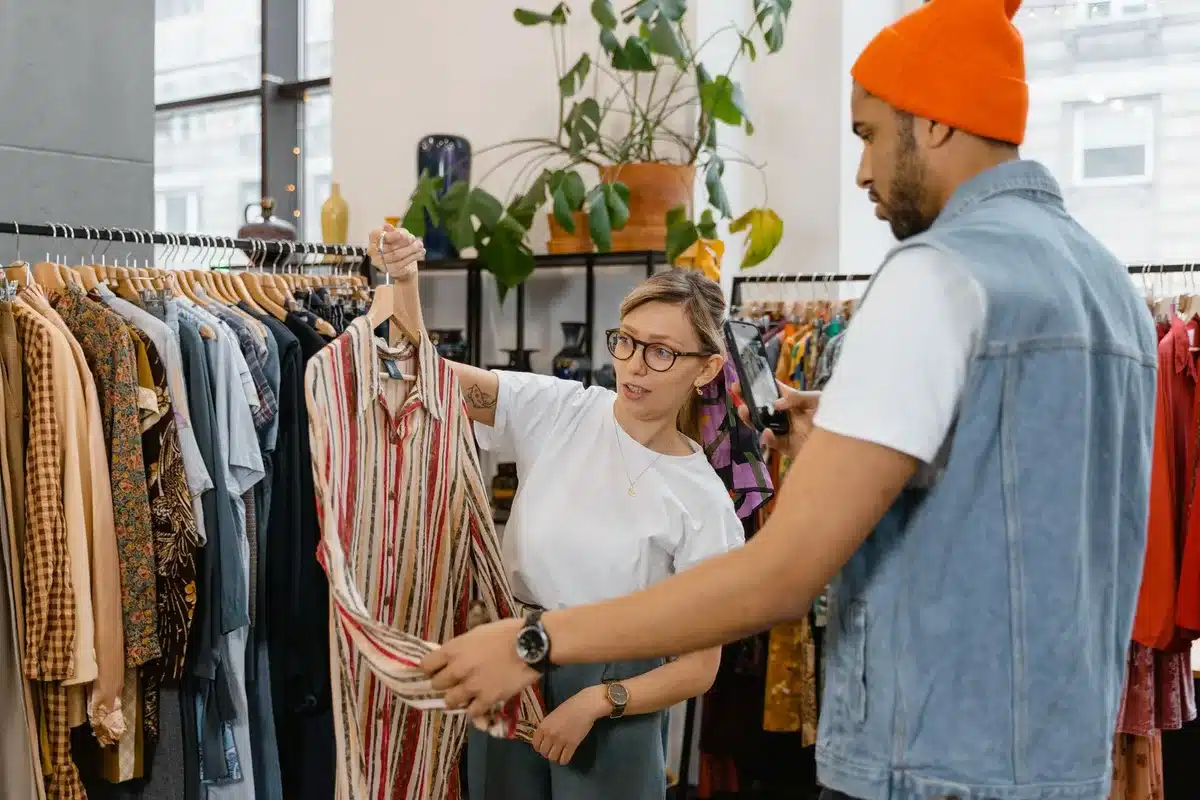 Cliente siendo atendido en una tienda de ropa, pidiendo ayuda al vendedor