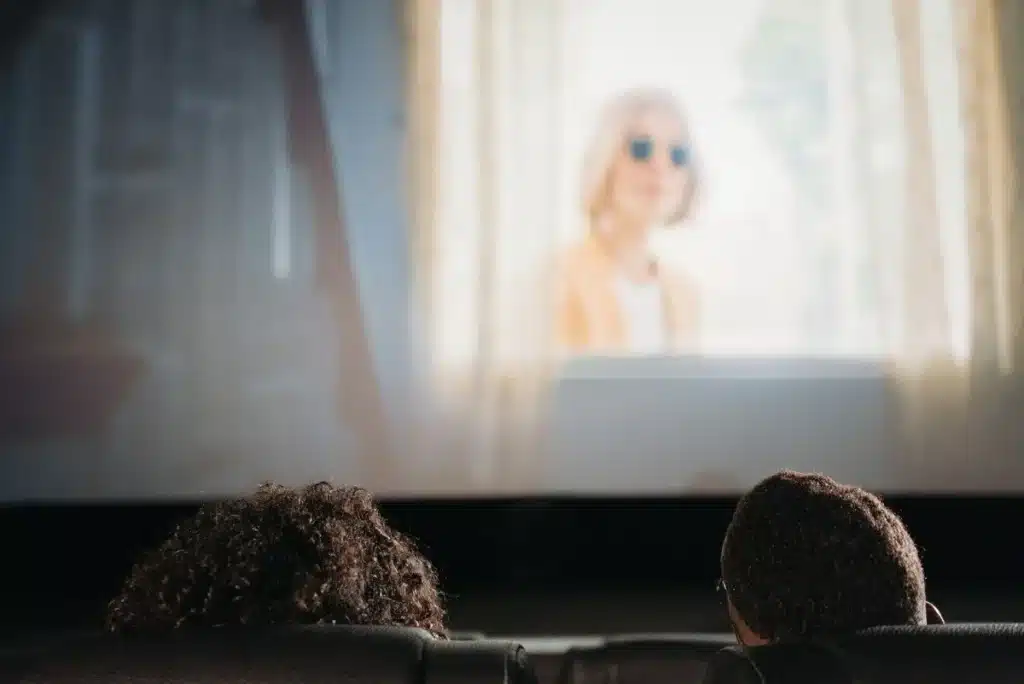 Familias y niños en la entrada de un cine con carteles de películas infantiles de verano