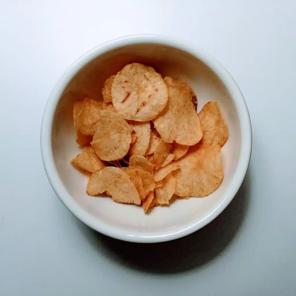 Cuencos de patatas fritas crujientes con diferentes sabores en una barra, con una bebida fría al lado