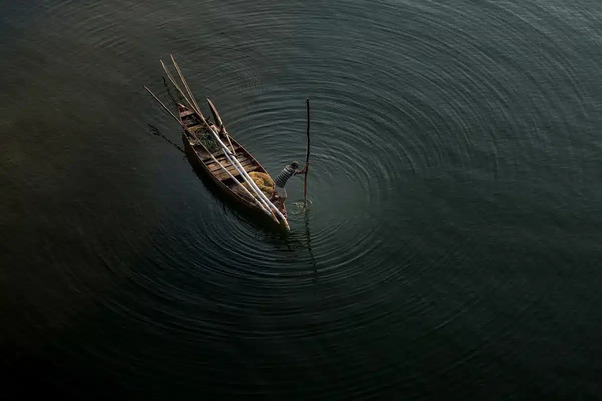 Vista lejana de un pueblo costero islandés con casas y un barco pesquero bajo luz diurna